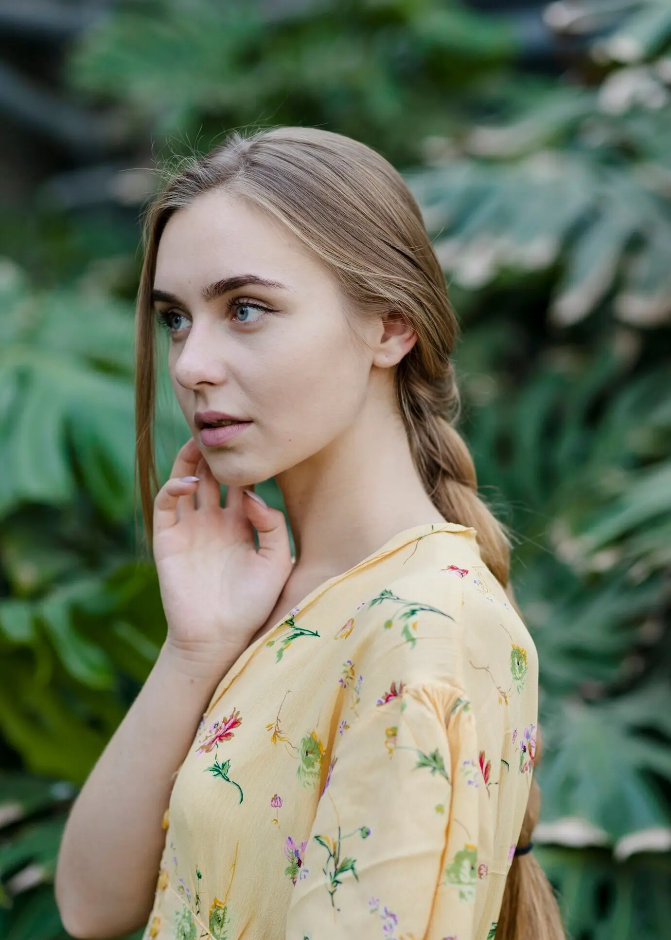 Seitliche Ansicht einer jungen Frau, die in einem Gewächshaus posiert.